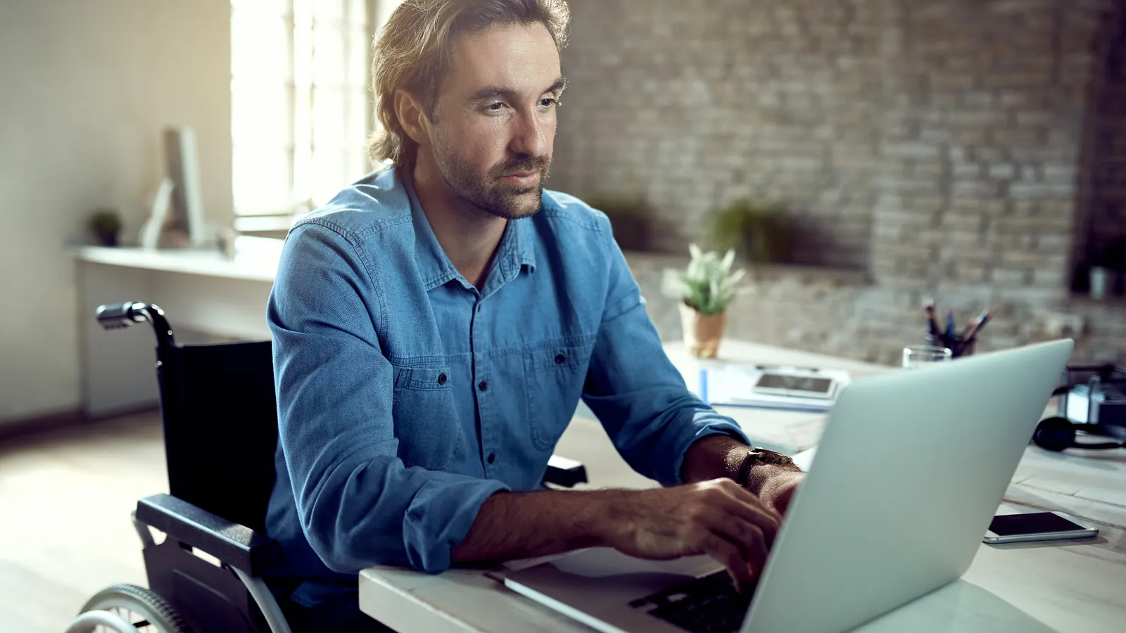 Homme en fauteuil roulant qui travaille sur un ordinateur portable