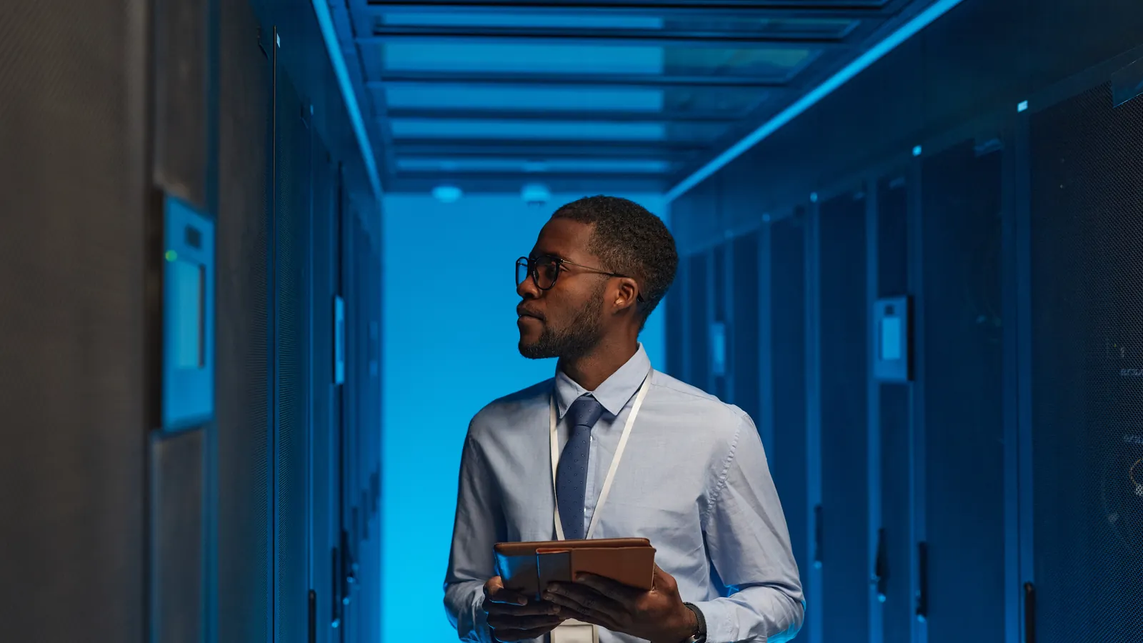 Technicien avec une tablette dans une salle de serveurs d'un data center