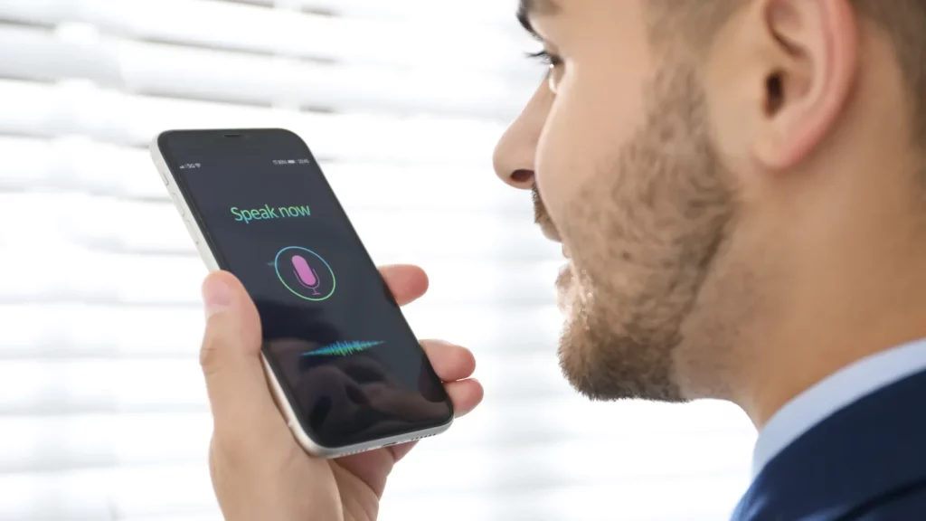 Homme qui dicte une demande à un assistant vocal sur son smartphone