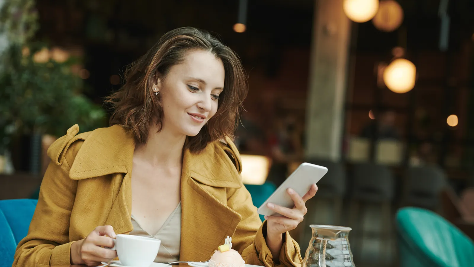 Femme qui consulte son smartphone dans un café